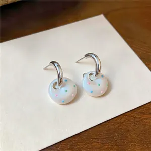 Détail de boucles d'oreilles en argent avec pendentifs donuts blancs à pois colorés