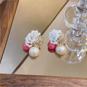 Macro view of handmade beaded pearl earrings with red accent stones for elegant women