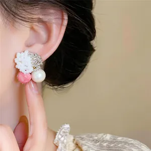 Close-up of elegant beaded pearl stud earring worn on ear with pink stone detail