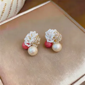 Close-up detail of handmade beaded cluster earrings with pearls on a golden metallic surface