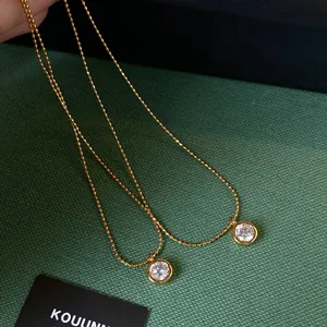 Dettaglio di collane placcate oro 18k con pendenti in zircone tondo su trama verde