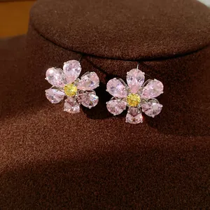 Detailed view of elegant pink and yellow zircon flower earrings on brown velvet stand