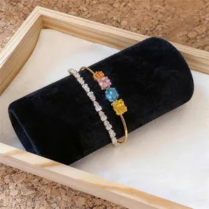 Detailansicht eines Goldarmreifs mit bunten quadratischen Zirkonia und Tennisarmband