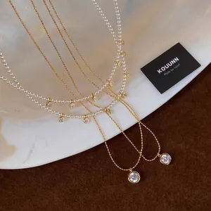 Dettaglio macro di un elegante set di collane placcate oro 18k con perle e zirconi fini.