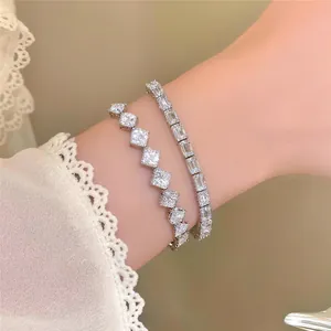 Exquisite Detailansicht eleganter, silberfarbener Zirkon-Viereck-Armbänder am Handgelenk.