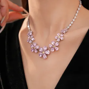 Close-up detail of a pink zircon flower necklace on an elegant model