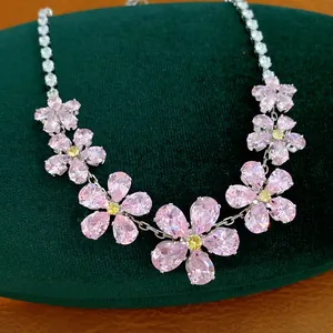 Elegant detail view of a pink zircon flower necklace on a green velvet jewelry display
