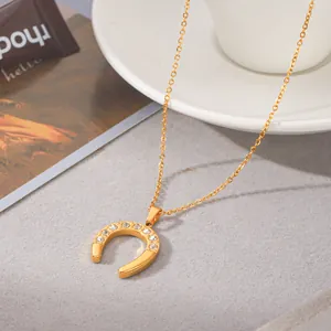 Close-up detail of a vintage gold horseshoe pendant necklace with clear rhinestones.