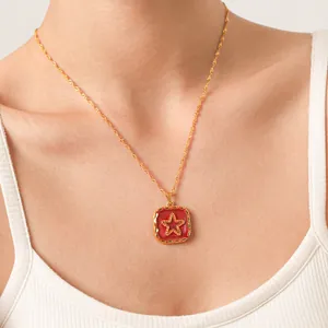 Detail of a vintage gold-toned necklace with a red enamel square pendant featuring a star.