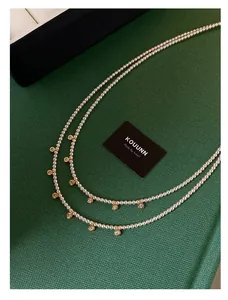 Primo piano di un'elegante collana di perle a due strati con ciondoli in zircone placcato oro