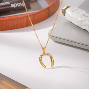 Close-up detail of golden horseshoe U-shaped pendant necklace with sparkling cubic zirconia