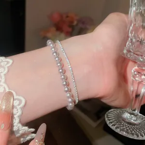 Nahaufnahme eines eleganten zweilagigen Perlen- und Zirkon-Armbands am Handgelenk