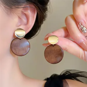 Nahaufnahme von Retro-Holzohrringen mit geometrischen Anhängern und Goldakzenten.