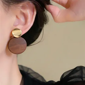 Detailansicht von retro geometrischen Holzohrringen am Model mit poliertem Goldakzent