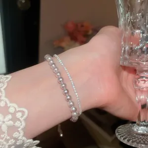 Detailansicht eines zweilagigen Armbands mit Perlen und funkelnden Zirkonia am Handgelenk.