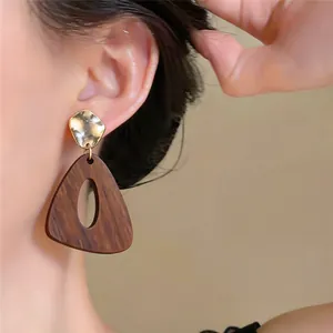 Nahaufnahme von geometrischen Holzohrringen im Vintage-Stil mit gehämmertem Gold-Finish