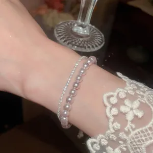 Detailansicht eines zweireihigen Perlen- und Zirkonia-Armbands mit Spitzenärmel.