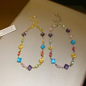 Close-up of gold and silver bracelets with colorful rhombus and oval-shaped zircons.