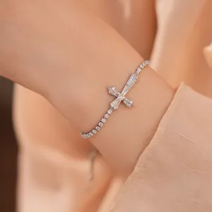 Detailweergave van een elegante zilveren kruisarmband met fonkelende zirkonia steentjes.