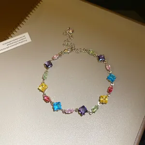 Close-up detail of a silver-tone chain bracelet featuring vibrant square and oval crystals