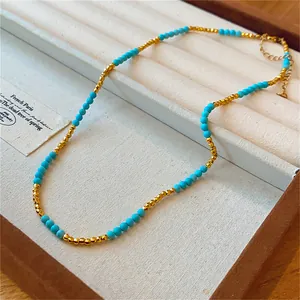 Détail en gros plan d'un collier de perles en métal plaqué or 18 carats et turquoise