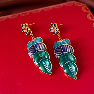 Nahaufnahme von Vintage-Blumen- und Blattohrringen mit blauen und grünen Emailledetails