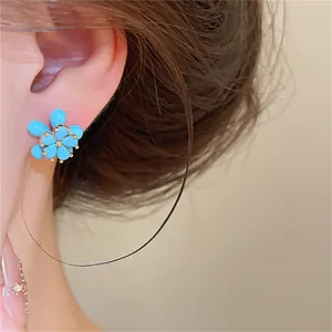 Vue rapprochée d'une boucle d'oreille fleur en pierre bleue plaquée or 18 carats