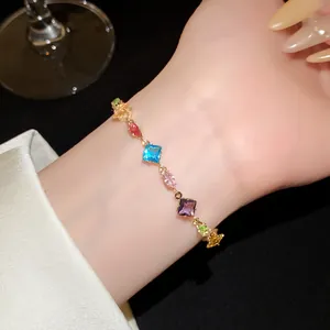 Close-up of a colorful gemstone bracelet with diamond and oval charms on wrist