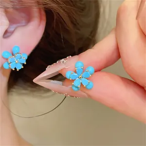 Vue détaillée de boucles d'oreilles en forme de fleur bleue avec accents dorés