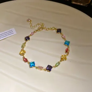 Detailed view of gold bracelet featuring multi-colored square and oval cubic zirconia stones