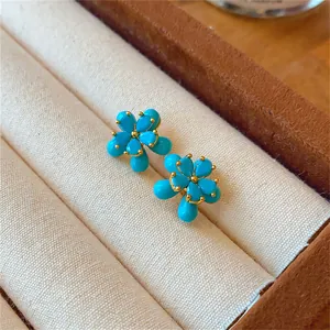 Vue détaillée de boucles d'oreilles fleurs vintage avec pierres turquoise et plaqué or 18 carats