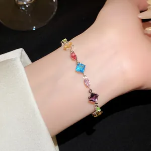 Macro detail showing colorful geometric zircon stones on a silver-tone chain bracelet