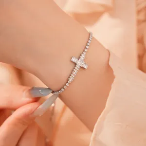 Detailopname van een zilveren zirkonia kruisarmband om een pols