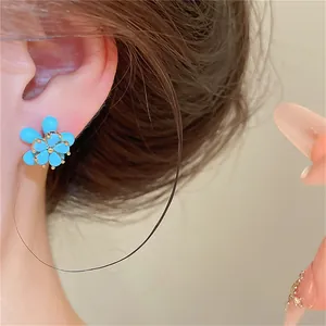 Détail d'une boucle d'oreille fleur en pierre bleue avec placage or 18 carats sur un mannequin