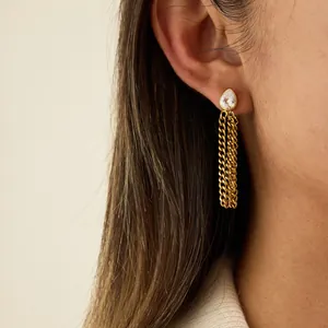 Vue détaillée de boucles d'oreilles dorées à pampilles avec un zircon sur modèle