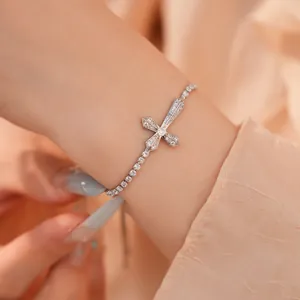 Gedetailleerde opname van een fonkelende zilveren armband met kruishanger en zirkoniasteen