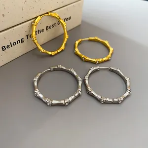Detailed view of gold and silver bamboo-joint hoop earrings with sparkling zircons.