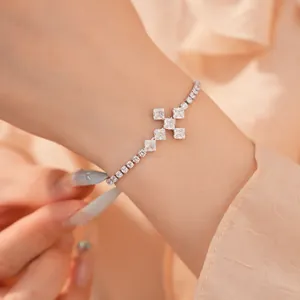 Detailweergave van een zilveren kruisarmband met zirkonia-stenen gedragen om de pols