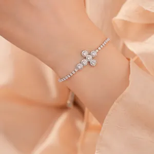 Zilveren kruis tennisarmband met fonkelende zirkonia's op pols met perzikkleurige stof