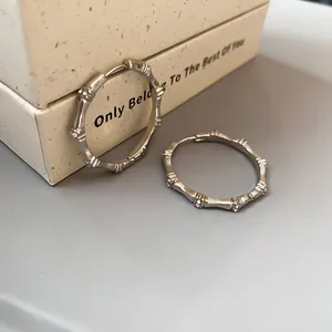 Detail view of silver-toned bamboo shaped hoop earrings decorated with shimmering zirconia stones.