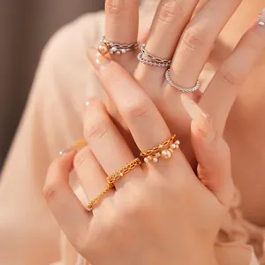 Detail von eleganten, 18 Karat vergoldeten Perlen- und Zirkonia-Ringen an Fingern.
