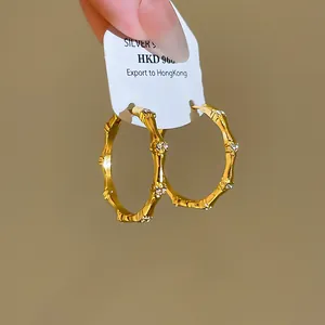 Exquisite close-up of bamboo-shaped gold hoop earrings with sparkling zircon details