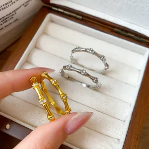Detailed view of elegant gold and silver bamboo joint hoop earrings with zircons in box