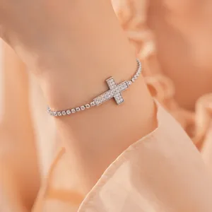 Gedetailleerde close-up van een zilveren tennisarmband met een glanzende kruishanger