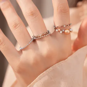 Nahaufnahme von 18 Karat vergoldeten Ringen mit Zirkon und Perlen an der Modellhand