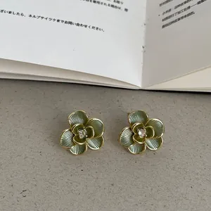 Gros plan élégant de boucles d'oreilles fleurs en plaqué or 14k vert avec cristal central