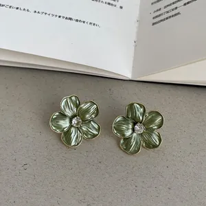 Vue rapprochée de boucles d'oreilles fleurs vertes avec bordure perlée dorée
