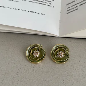 Gros plan de boucles d'oreilles fleur verte vintage plaqué or 14k avec centre cristal