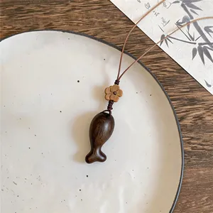 Makro-Detailansicht einer Fischkette aus dunklem Holz mit Blumenperle im Zen-Stil-Ambiente.