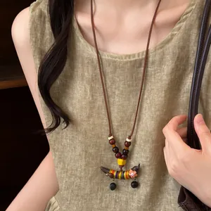 Détail d'un collier ethnique vintage avec des perles en bois et un pendentif de pois.